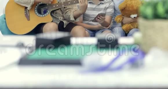 快乐的亚洲父亲在家为家人弹吉他视频的预览图
