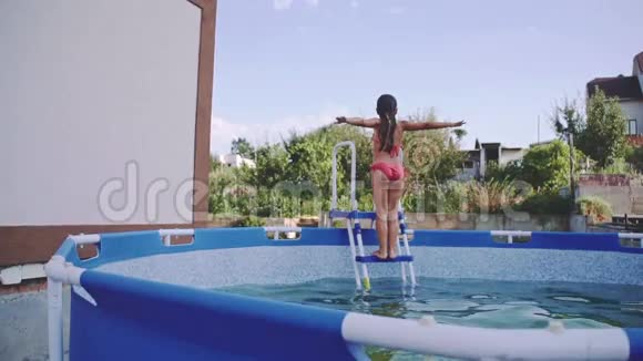 快乐的小女孩在户外游泳池里玩得很开心慢运动240fps孩子跳着玩视频的预览图