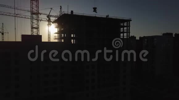 日落时的建筑工地建筑物附近建筑起重机的剪影视频的预览图