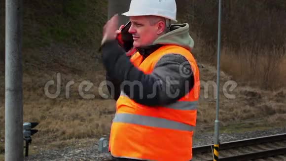 铁路员工在路过的火车旁用手机交谈视频的预览图
