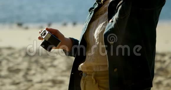 女子在沙滩4k处用相机点击照片视频的预览图