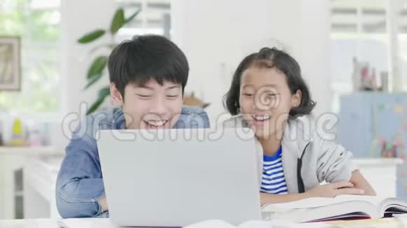小男孩正在用电脑教和解释家庭作业给有表情和快乐手势的朋友视频的预览图