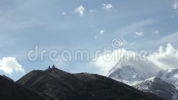 在浮云和卡兹别克山背景下的圣三位一体Gergeti神庙的景观格鲁吉亚高加索视频的预览图