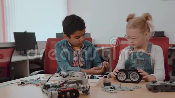 混合种族群体的学校孩子坐在课堂与DIY机器人茎教育的概念视频的预览图
