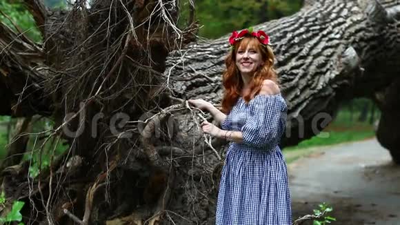 戴着花环的女孩在一棵倒下的树的背景上微笑视频的预览图