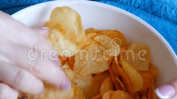 女性漂亮整洁的手与法国美甲从深盘中取出薯片不健康食品快餐视频的预览图