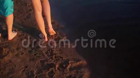 年轻可爱的夫妇赤着脚在沙滩上散步视频的预览图
