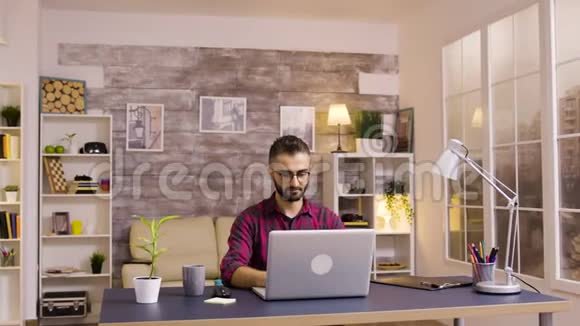 英俊的白种人自由职业者在家工作笔记本电脑视频的预览图