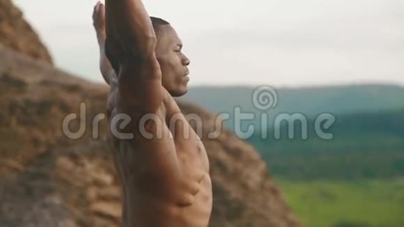 英俊的非裔美国健美运动员户外伸展的特写镜头山地景观背景视频的预览图