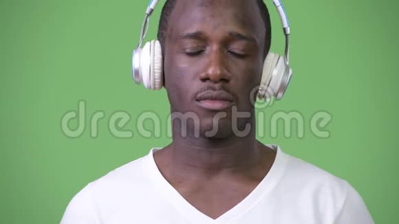非洲年轻人在绿色背景下听音乐视频的预览图