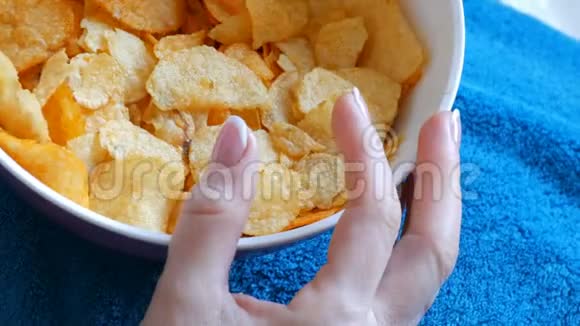 女性漂亮整洁的手与法国美甲从深盘中取出薯片不健康食品快餐视频的预览图