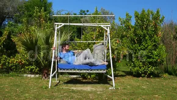 在花园里睡吊床的白种人摇摆摇摆视频的预览图