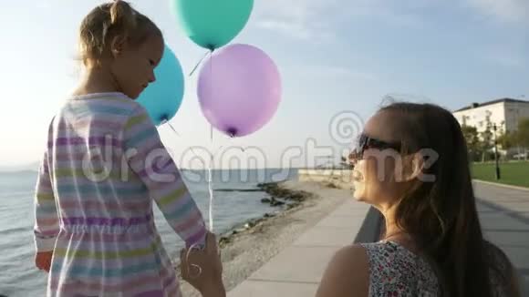 早晨女人和一个美丽的小女孩在海滨散步视频的预览图
