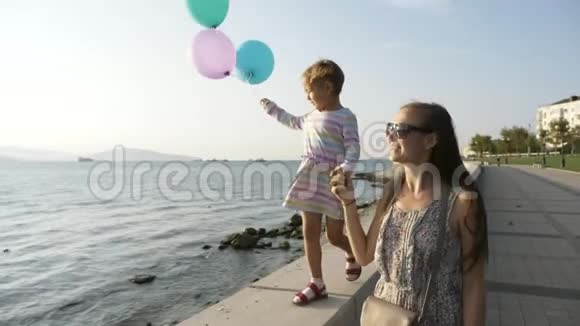 早晨女人和一个美丽的小女孩在海滨散步视频的预览图