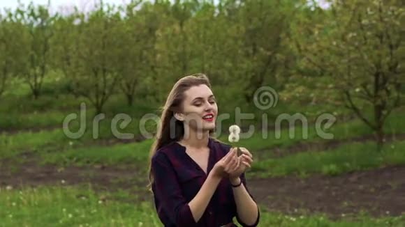 快乐的女孩在花园里吹蒲公英慢动作视频的预览图