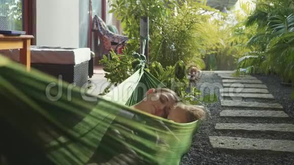 快乐的母女在夏日的花园里一起在吊床上放松视频的预览图