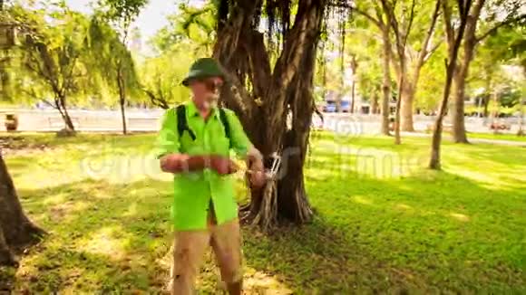 带包的帽子里长胡子的老人在公园里做自拍视频的预览图