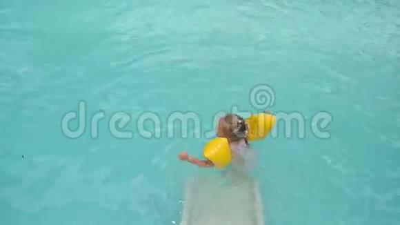 小女孩从滑水中滑入了蓝色的游泳池视频的预览图