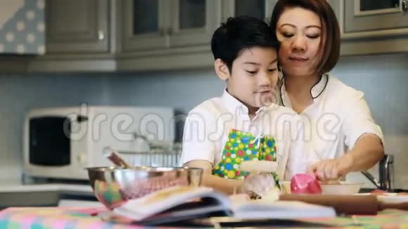 亚洲母亲的肖像和儿子一起做巧克力饼干多莉拍摄视频的预览图