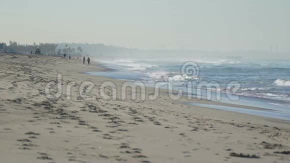 人们沿着圣莫尼卡码头附近的海滩散步视频的预览图