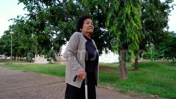 在公园里用手杖走路的老年妇女的慢动作视频的预览图