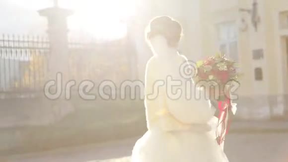 在巴洛克教堂附近美丽的天真的黑发新娘摆着结婚花束视频的预览图
