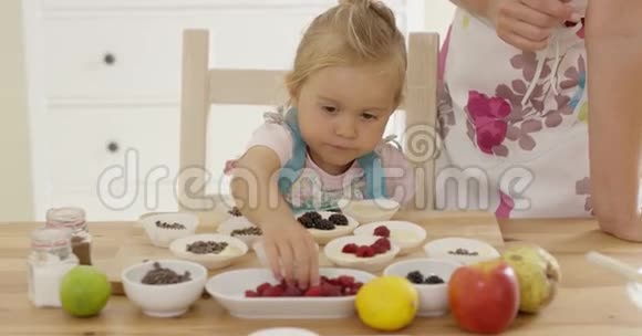 小女孩把浆果放在松饼上视频的预览图