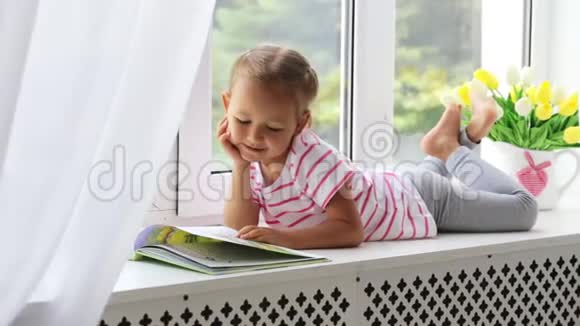 特写小可爱女孩在家窗台上看书的画像视频的预览图
