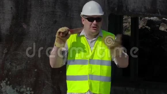 愤怒的建筑工人用大锤在墙边说话视频的预览图