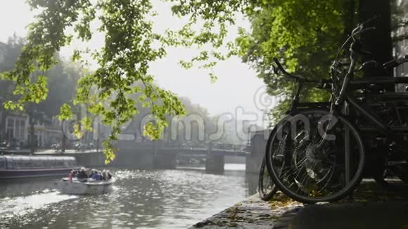 阿姆斯特丹阿姆斯特尔运河上的自行车轮景旁边是漂浮的旅游船阳光明媚的欧洲秋天视频的预览图