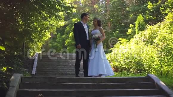 新娘和新郎正沿着公园小巷散步视频的预览图