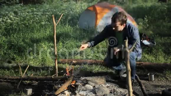 人在露营时把木头扔在火上清晨在森林里视频的预览图