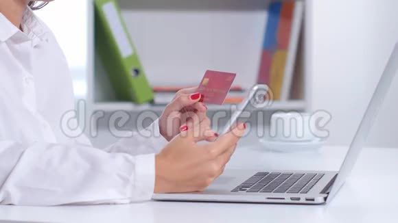 女孩在办公室里用手机和笔记本电脑在线购买关门视频的预览图