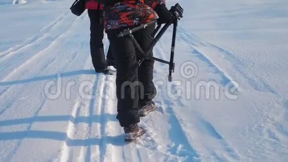 团队合作男游客摄影师冬天乘三脚架爬山顶山顶山顶群去下雪视频的预览图