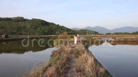 穿着越南服装戴帽子的金发女孩走在池塘之间视频的预览图