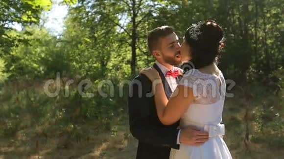 新郎新娘在美丽的绿色森林里接吻视频的预览图