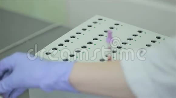 护士把一个现代化的试管和血液分析放在实验室瓶下的支架上视频的预览图