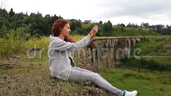 女孩在山上的老高架桥附近写短信视频的预览图