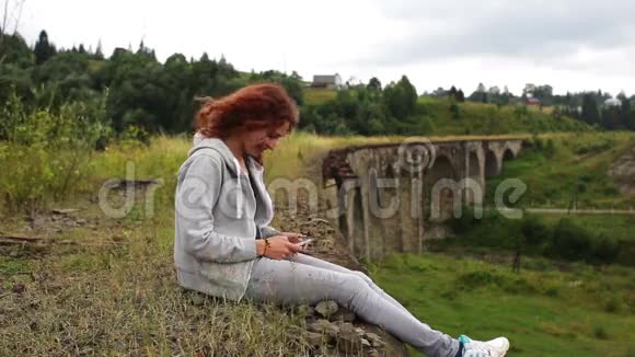 女孩在山上的老高架桥附近写短信视频的预览图