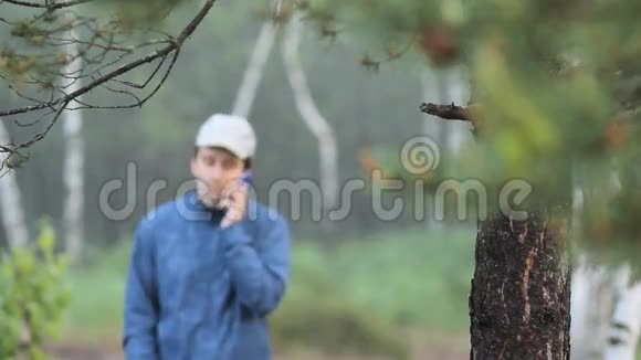 一个人在森林里的一棵树附近打电话清晨视频的预览图