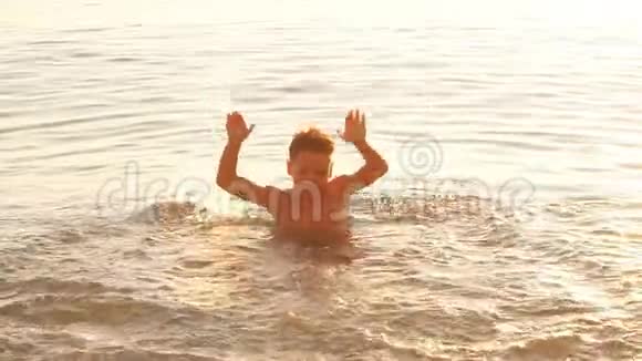 日落时在海上玩的男孩慢动作视频的预览图