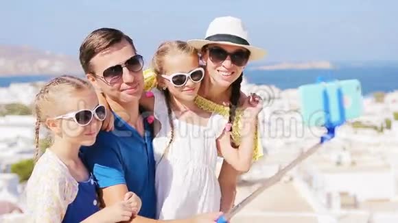 家庭度假在欧洲父母和孩子自拍照片背景Mykonos镇希腊视频的预览图