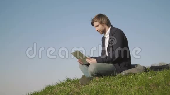 年轻人用笔记本电脑在公园草地上聊天视频的预览图