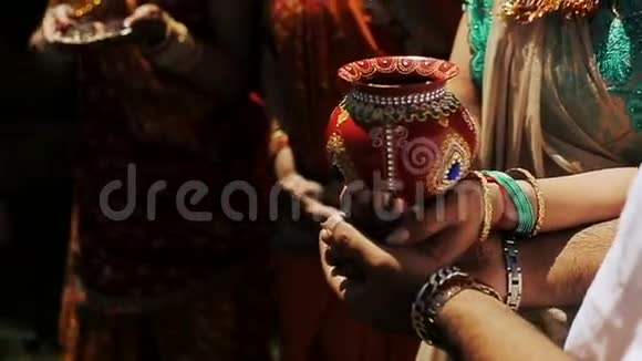 印度新娘和她的父母手里拿着珠宝的红碗视频的预览图