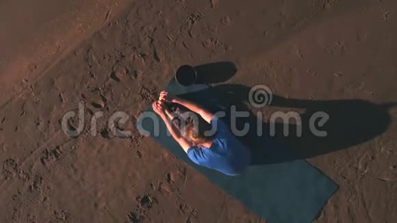 日落时在海滩上做瑜伽的人的空中视野视频的预览图