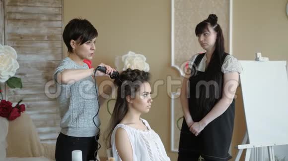 化妆师和模特一起工作理发师做模特的发型女人和一个设计师一起工作视频的预览图