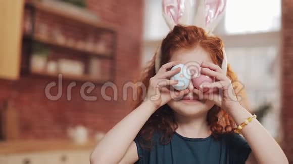 欢快的红头小女孩的肖像带着兔子耳朵厨房背景上有一个复活节彩蛋她是视频的预览图