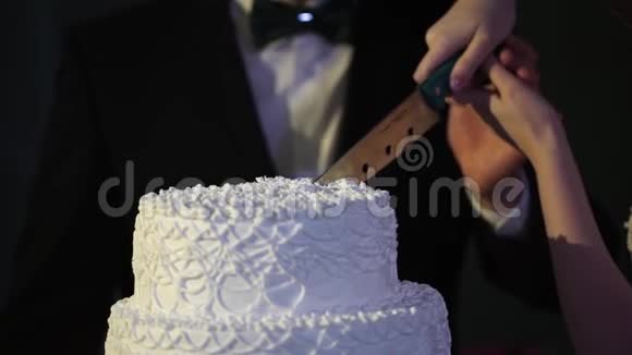 新娘和新郎的手切一片婚礼蛋糕新娘和新郎在婚宴上切婚礼蛋糕视频的预览图