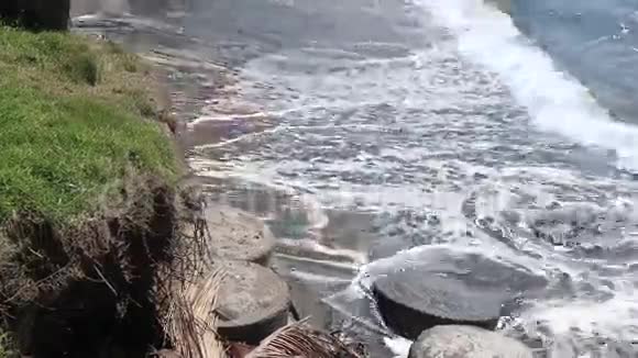 印度尼西亚巴厘岛热带岛屿上的黑色砂质熔岩海滩波浪在海岸线上被压碎美丽的深色背景视频的预览图