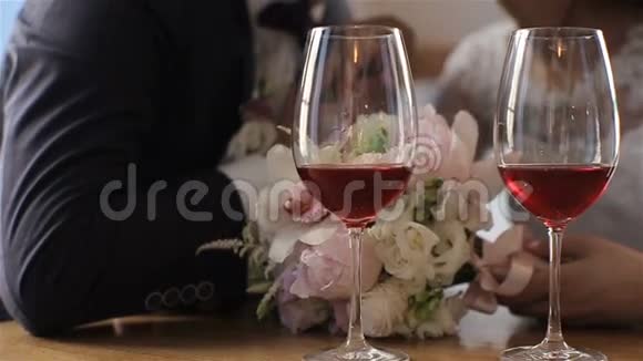 两杯红酒背景是一对美丽的婚礼夫妇慢动作视频的预览图